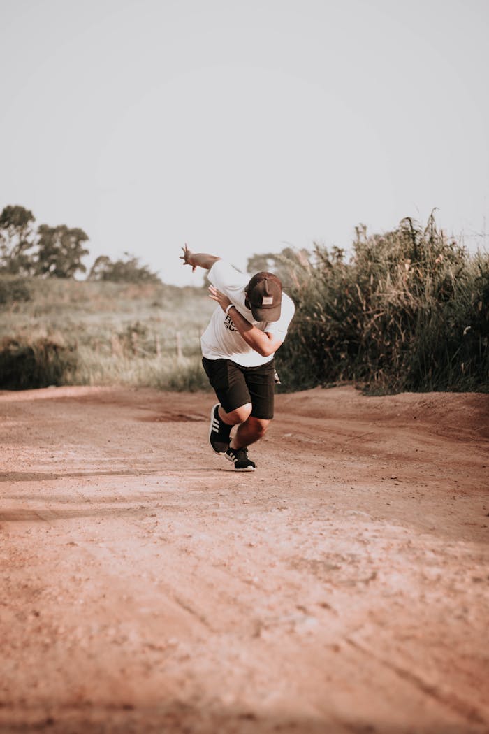 contact-hero A young man wearing casual attire runs on a dirt path surrounded by nature on a sunny day.